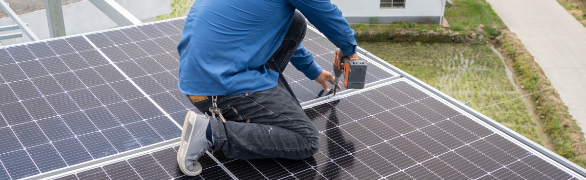 Man installing DIY solar panel kit on roof of home.